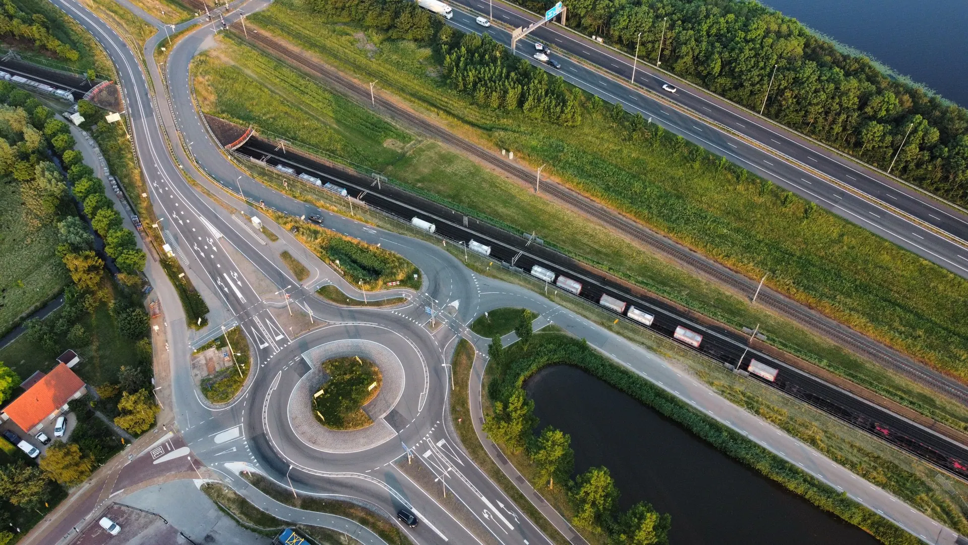Een rotonde met fietspaden van bovenaf, naast een snelweg