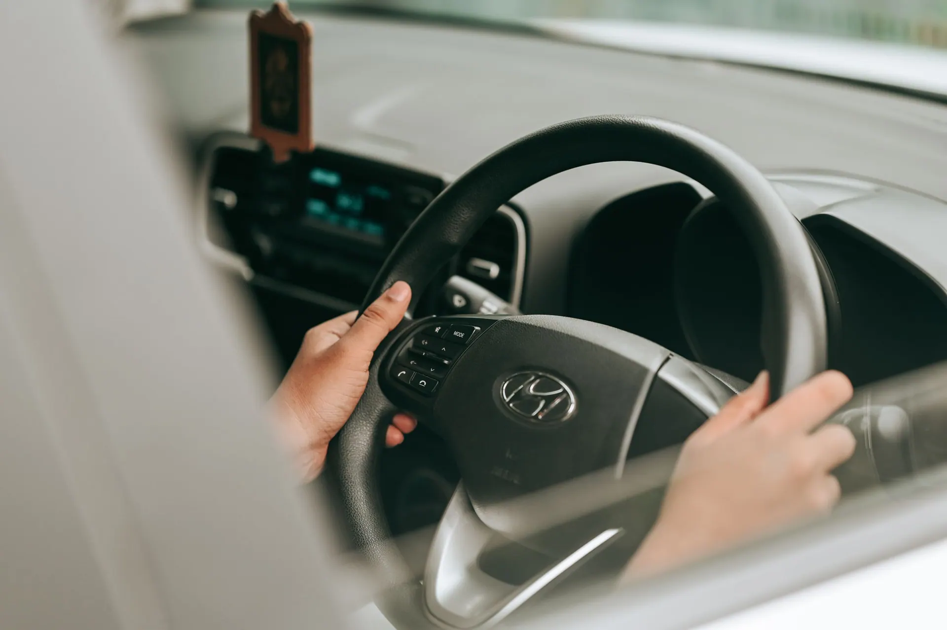 Handen aan het stuur van de handgeschakelde lesauto