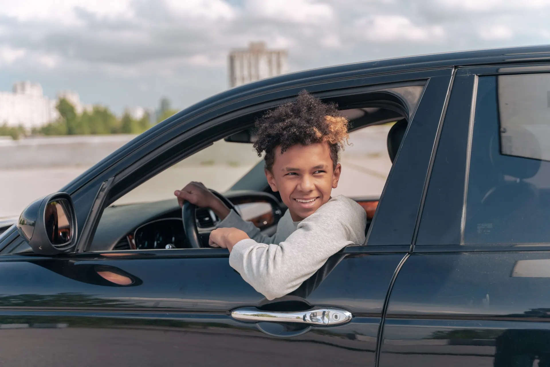 Een leerling lacht uit het raam van de lesauto na het examen