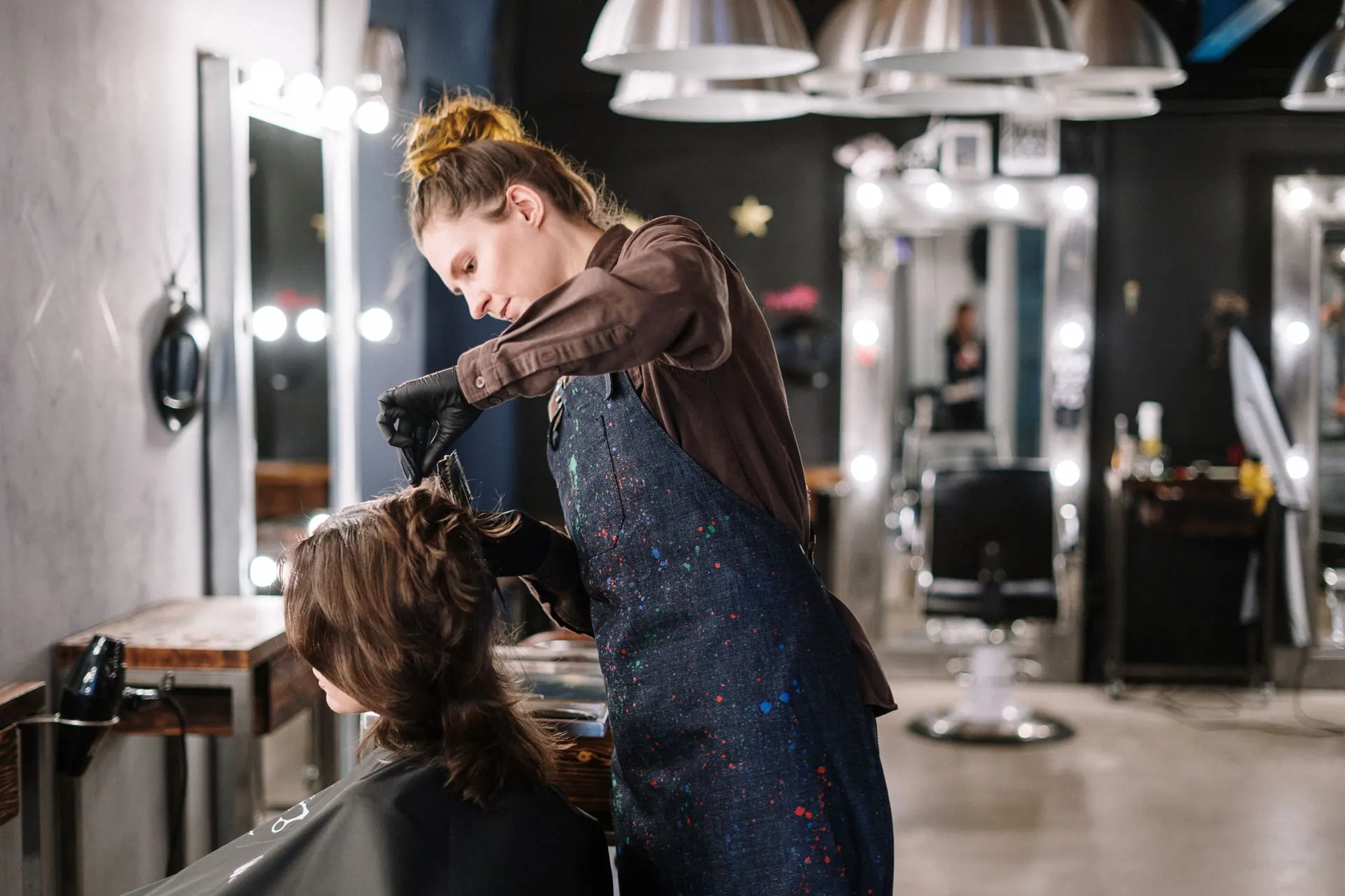 Een kapster brengt kleur aan bij een klant in de salon