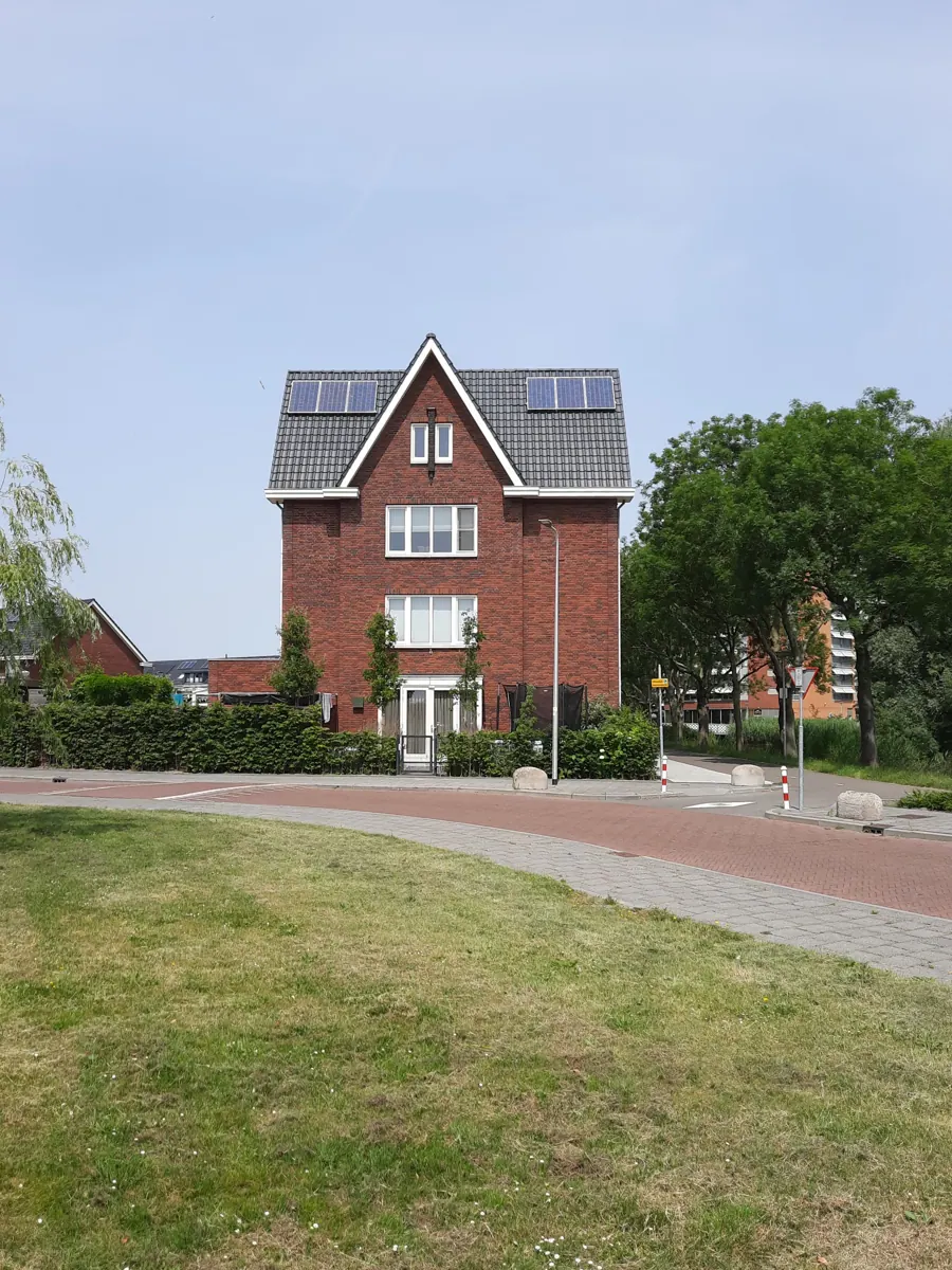 Rood bakstenen huis met zonnepanelen aan een rustige straat
