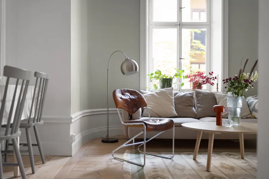 Lichte zitkamer met een leren stoel, planten en een radiator onder het raam