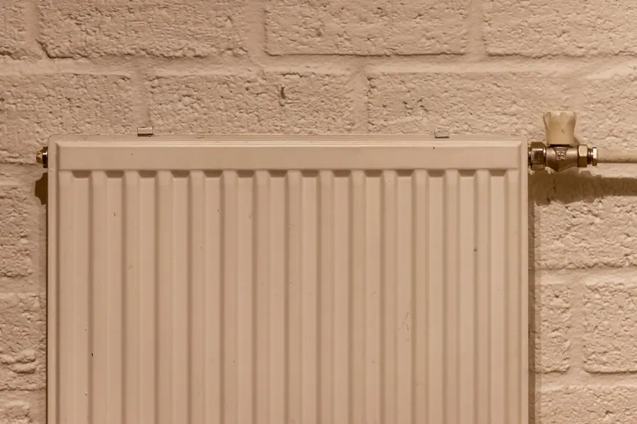 Lage-temperatuurradiator tegen een lichte bakstenen muur